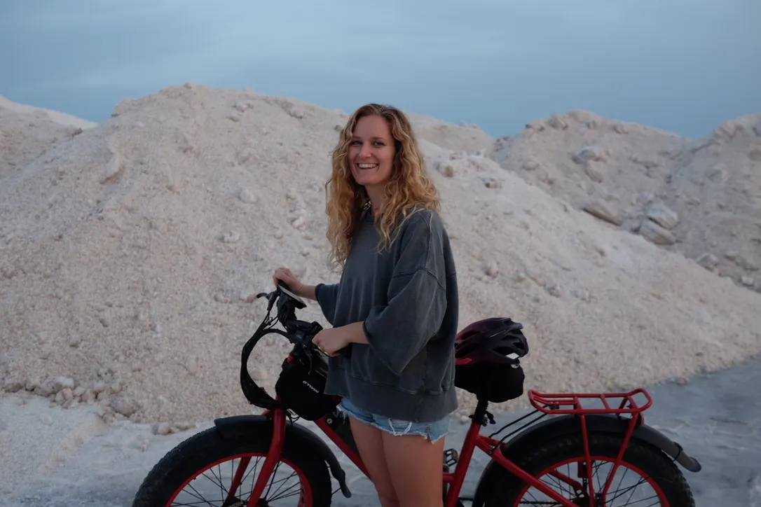 Eleonora outdoors at dusk, standing with a red bicycle